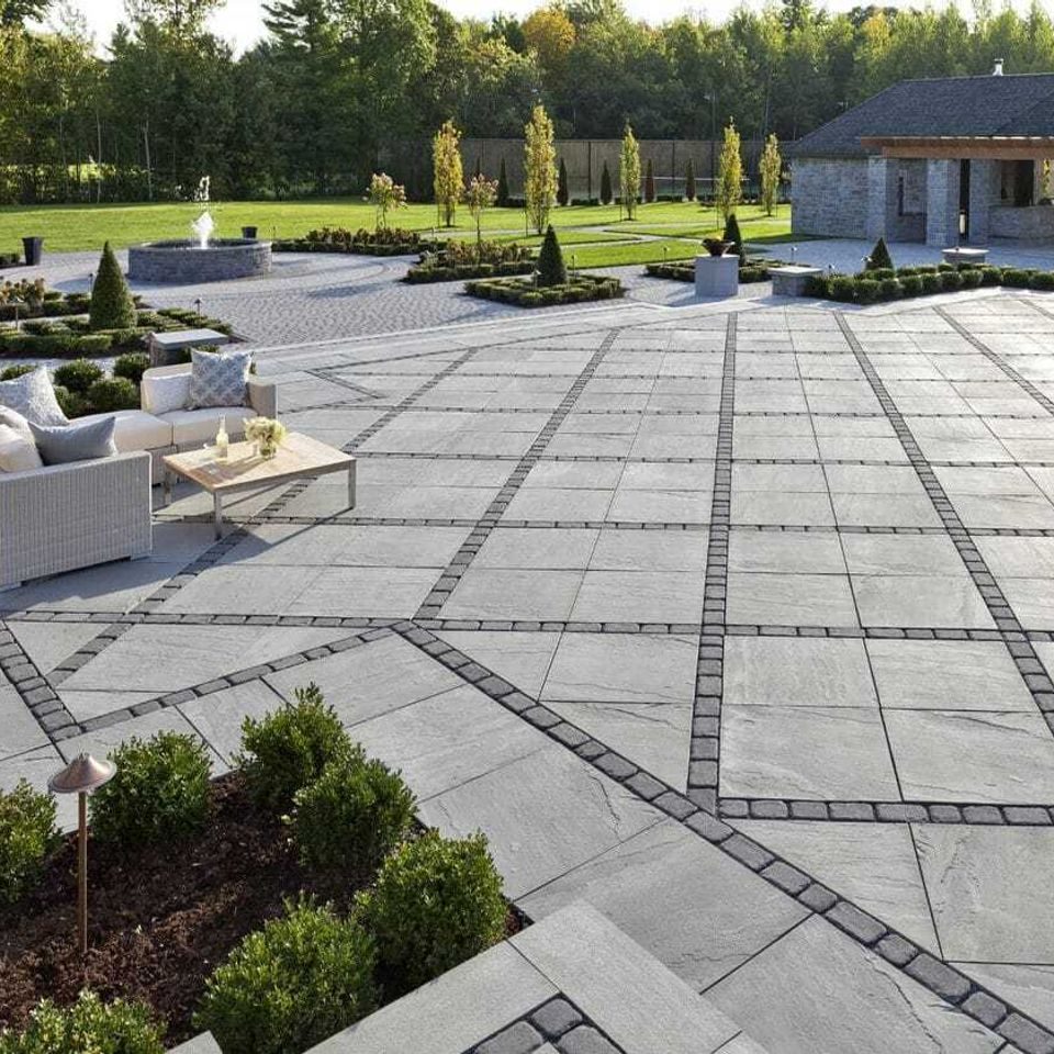 Formal grey slab terrace laid in a banded grid, with clipped boxwood along the edge