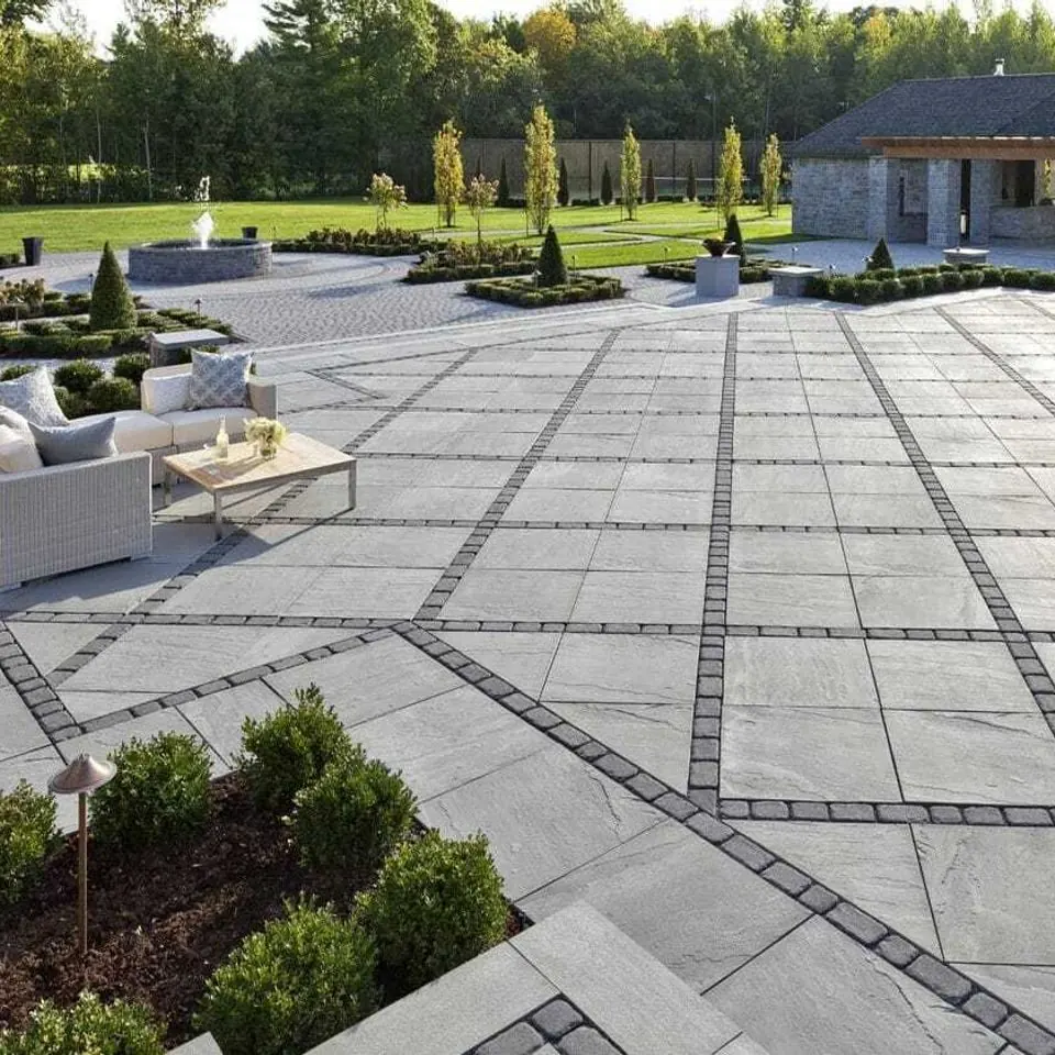 Formal grey slab terrace laid in a banded grid, with clipped boxwood along the edge