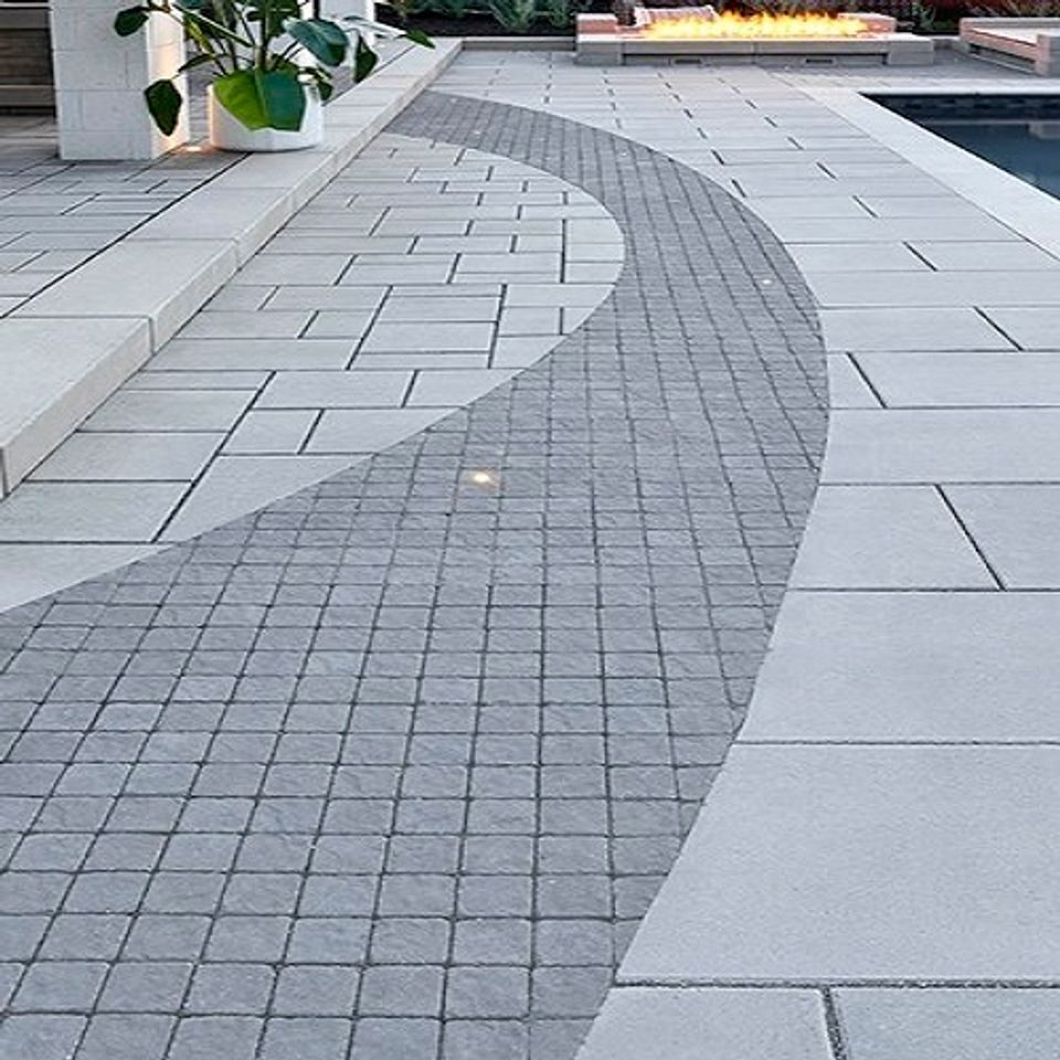 Curve of small cobble setts inlaid across a large-format grey slab pool deck