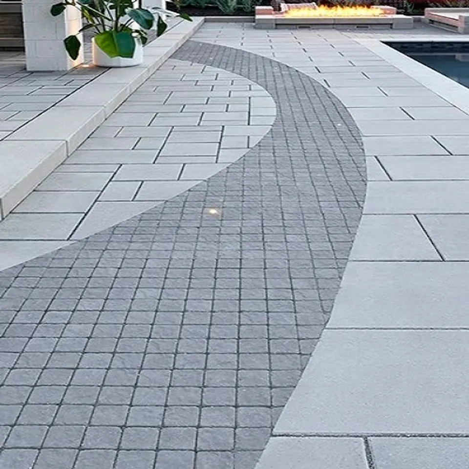 Curve of small cobble setts inlaid across a large-format grey slab pool deck