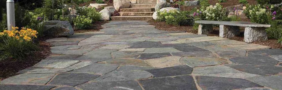 Bluestone flagstone paving leading between planting beds to a granite bench