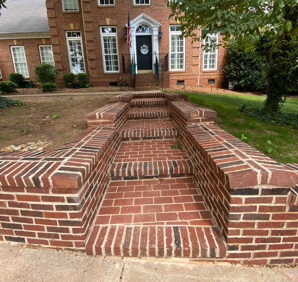 Brick steps and low cheek walls rising from the drive to a colonial home