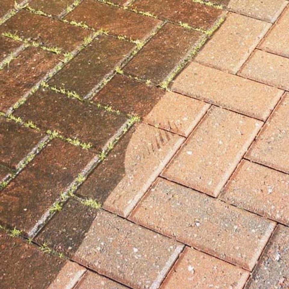 Close-up of brick pavers, weed-grown on one side and cleaned back to colour on the other