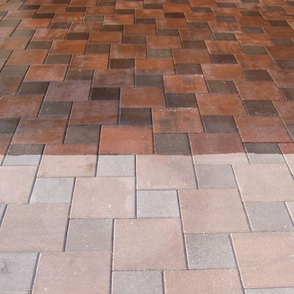 Paver surface half finished with a wet-look sealer, deepening the colour of the treated area