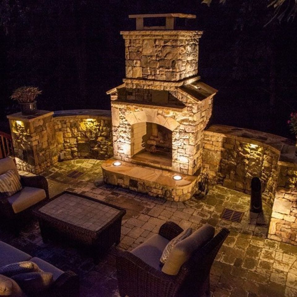 Outdoor fireplace and curved seat walls picked out by low lighting after dark