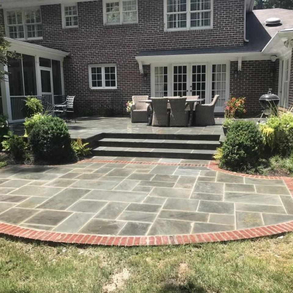 Bluestone patio ringed by a brick border, with steps up to a dining terrace