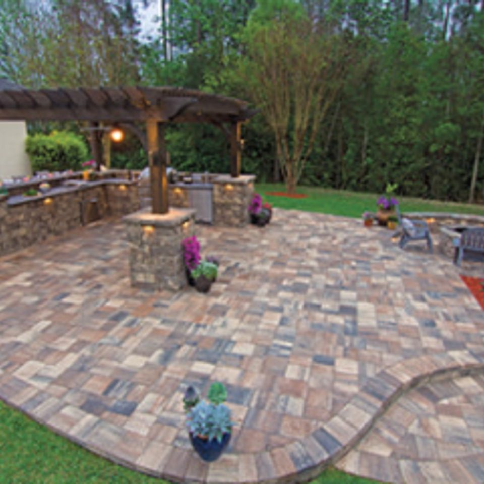 Multi-tone paver patio with a pergola over the outdoor kitchen and a fire pit at the far end