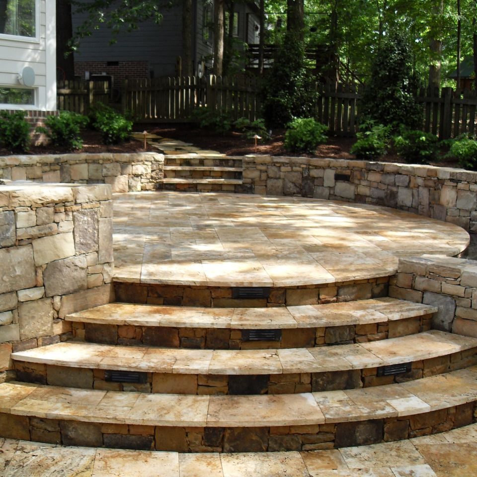 Curved stone steps with lit risers rising between stacked stone walls