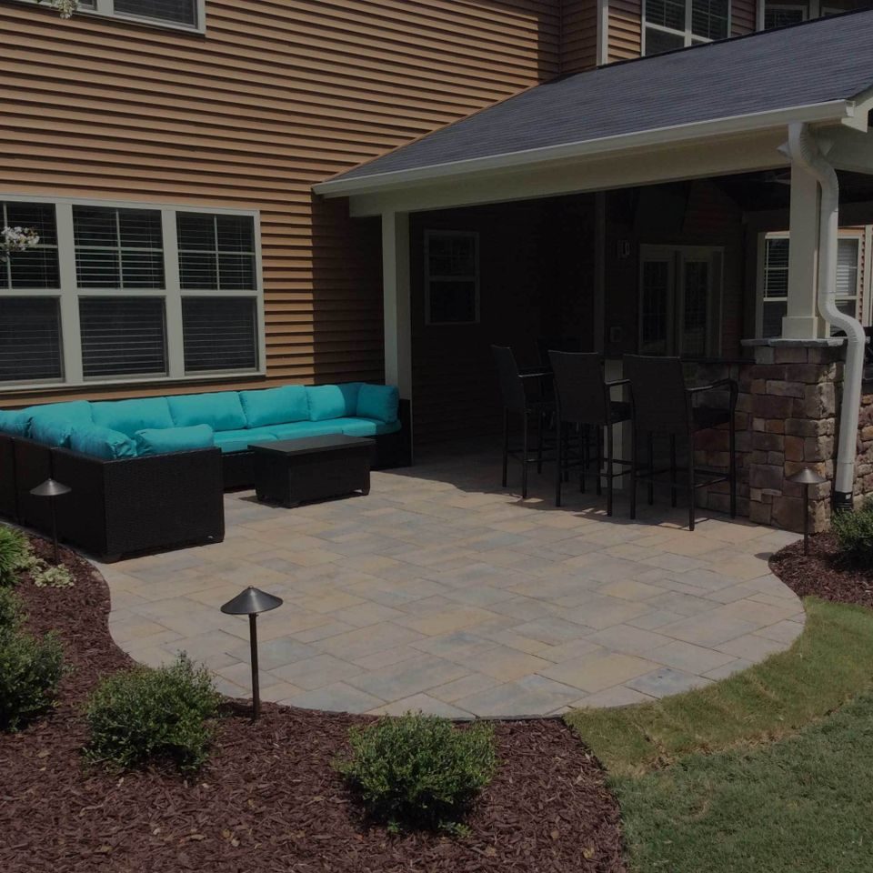 Paver patio with a turquoise sectional beside a covered porch bar