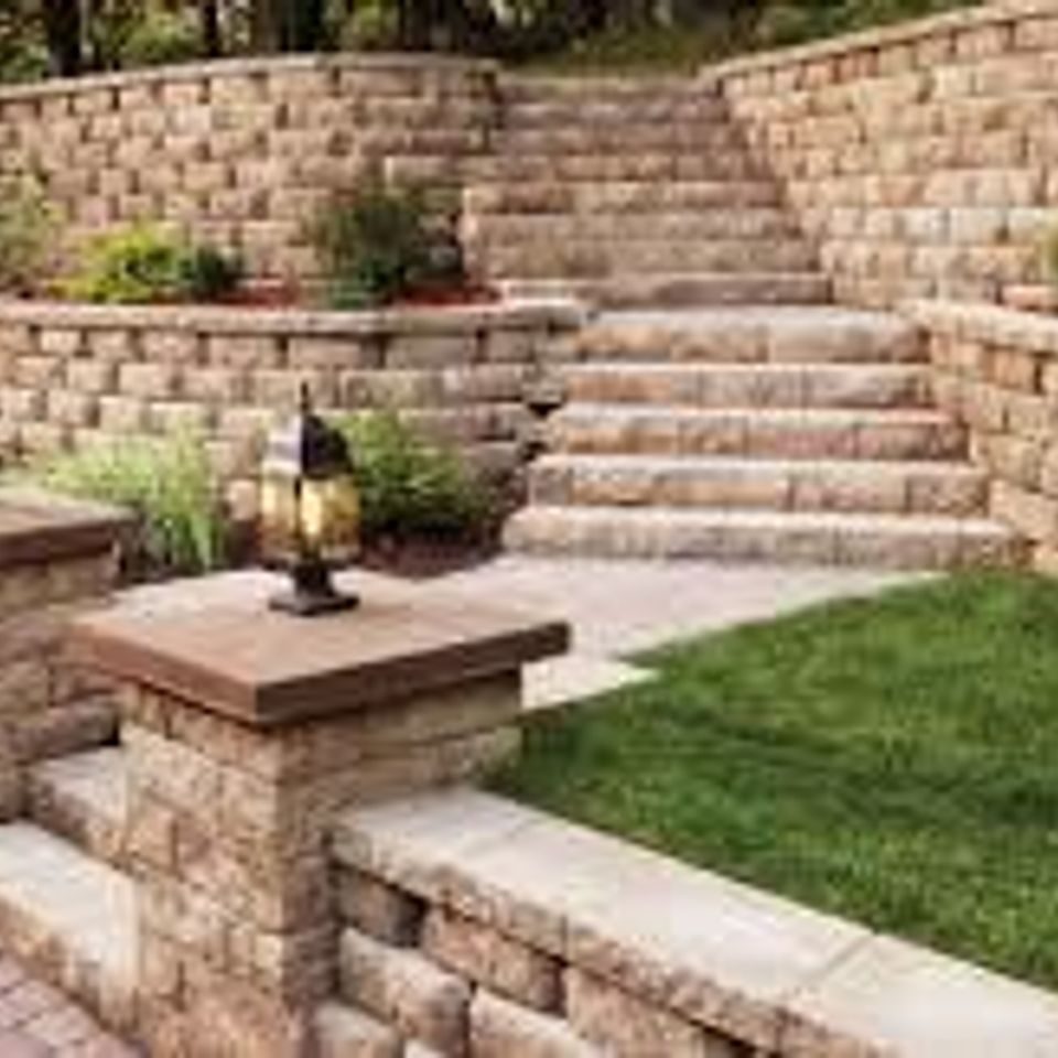 Block retaining walls and a wide flight of steps climbing past a lantern-topped pillar