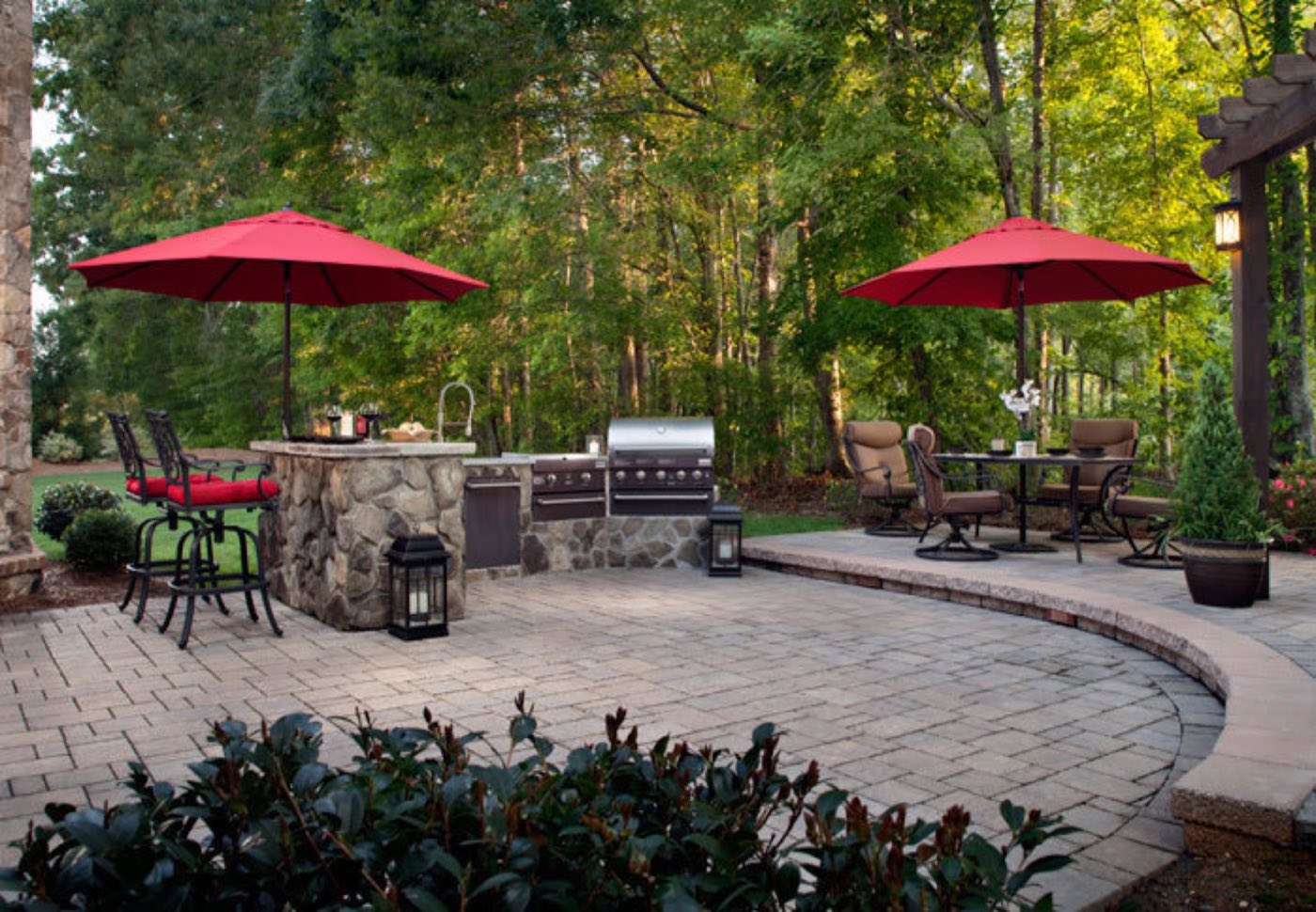 Paver patio with a fieldstone bar and grill island, curved seat wall and umbrella-shaded dining