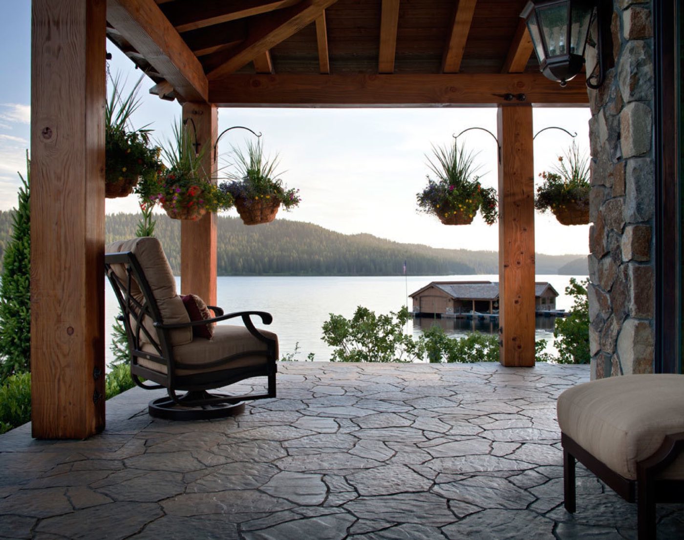 Timber pavilion with a flagstone-pattern paver floor looking out over a lake and boathouse