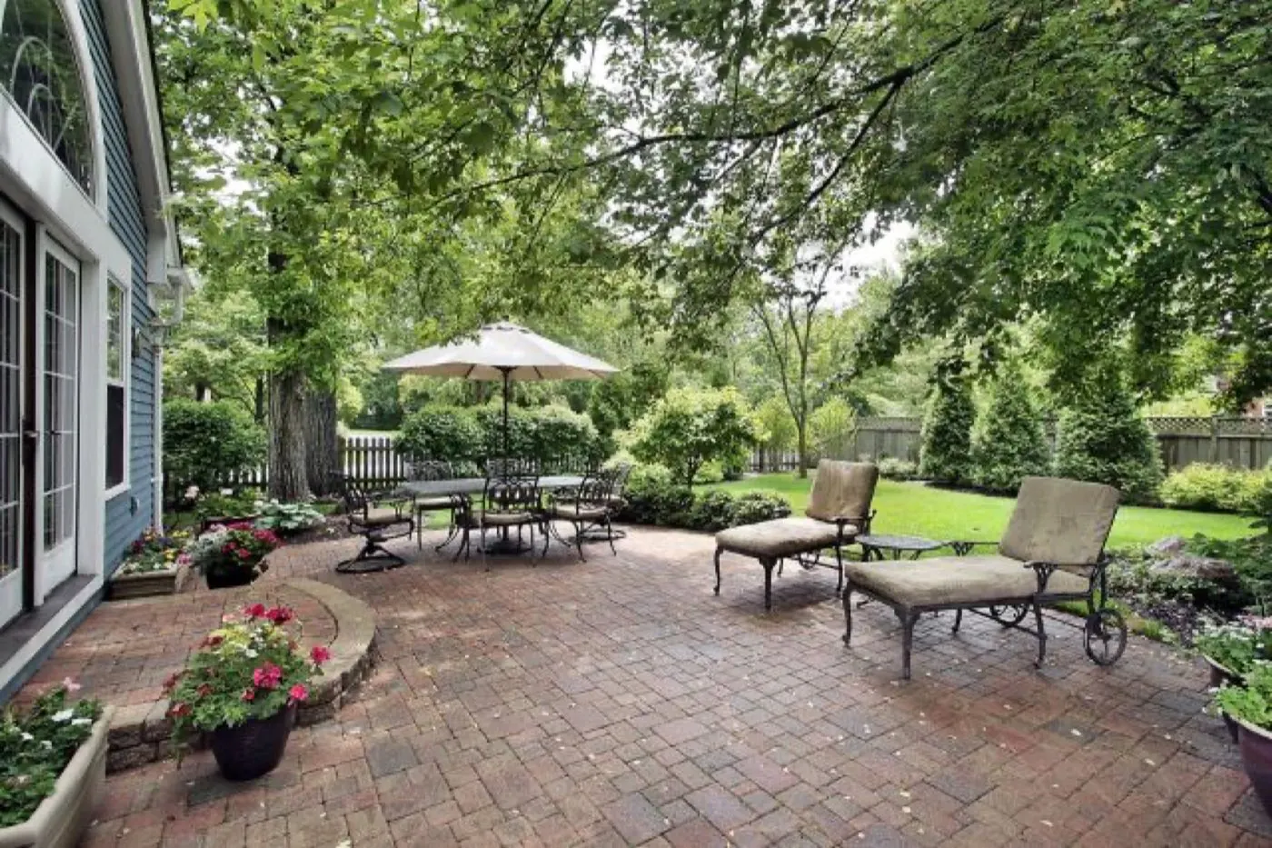 Clay brick paver patio with a curved planter wall and lounge seating at a Davidson home
