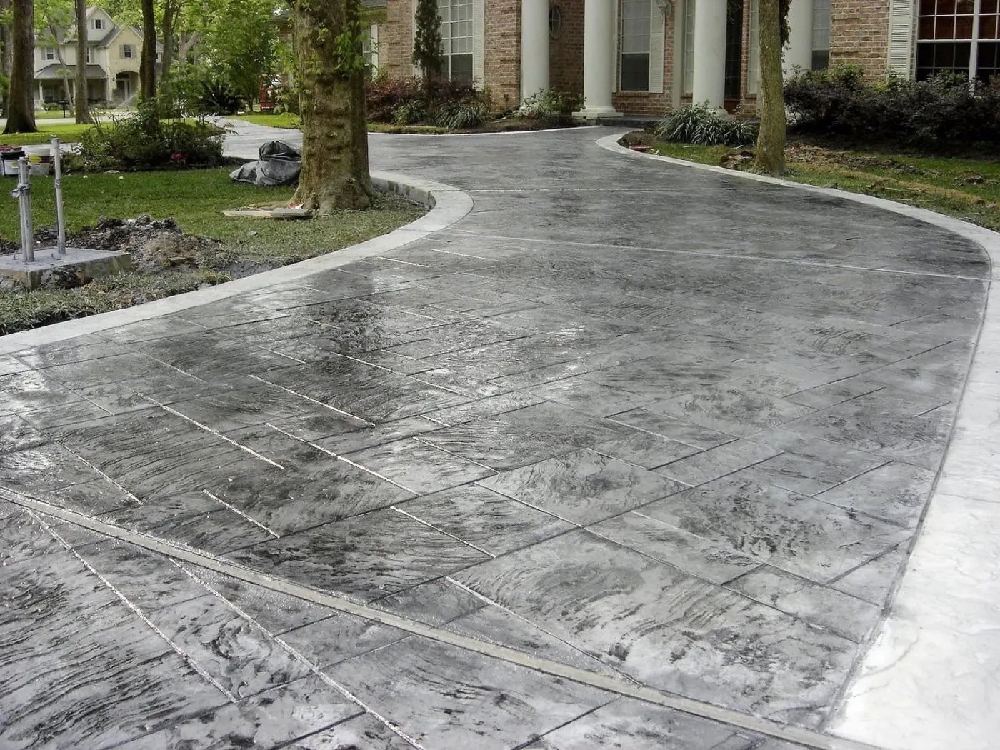 Stamped concrete driveway in a grey ashlar slate pattern curving to a columned entry