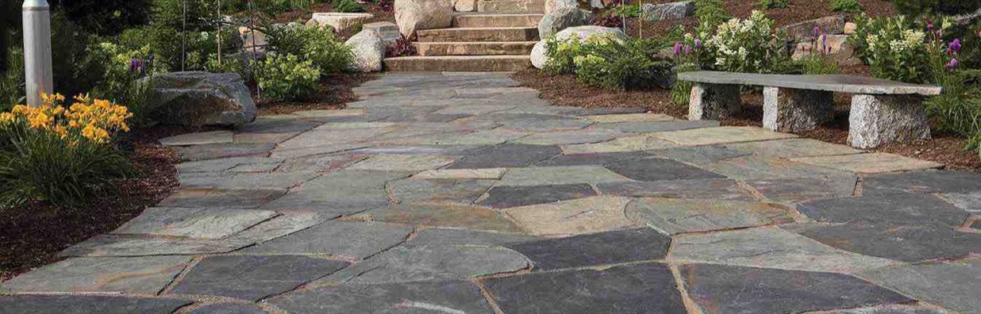 Irregular bluestone flagstone walk running past a granite bench toward a flight of steps
