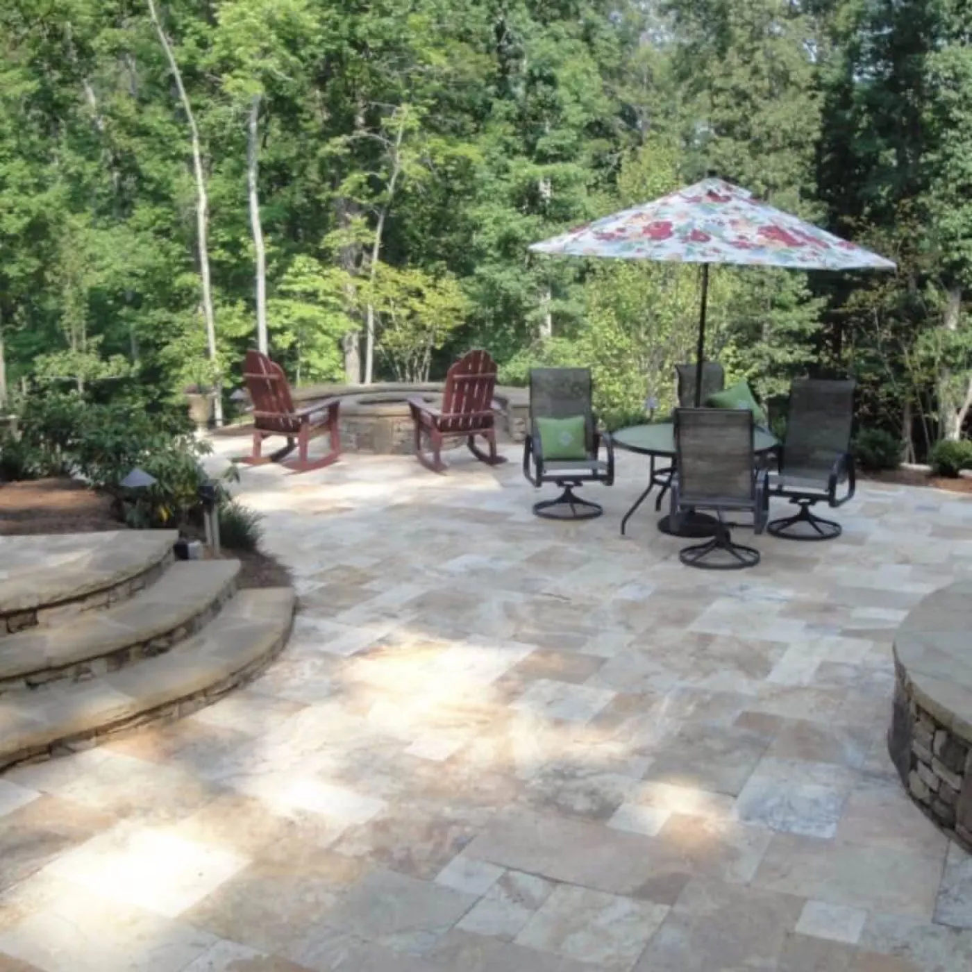 Travertine paver patio with a fire pit, stone steps and shaded dining on a wooded Huntersville lot