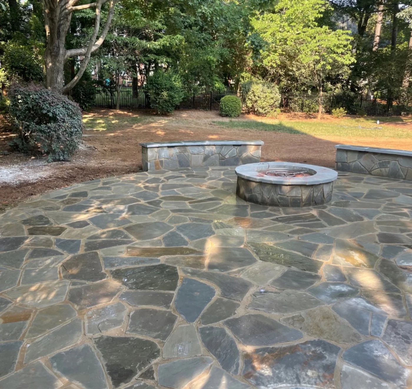Irregular bluestone patio with a round fire pit and curved seat walls capped in stone