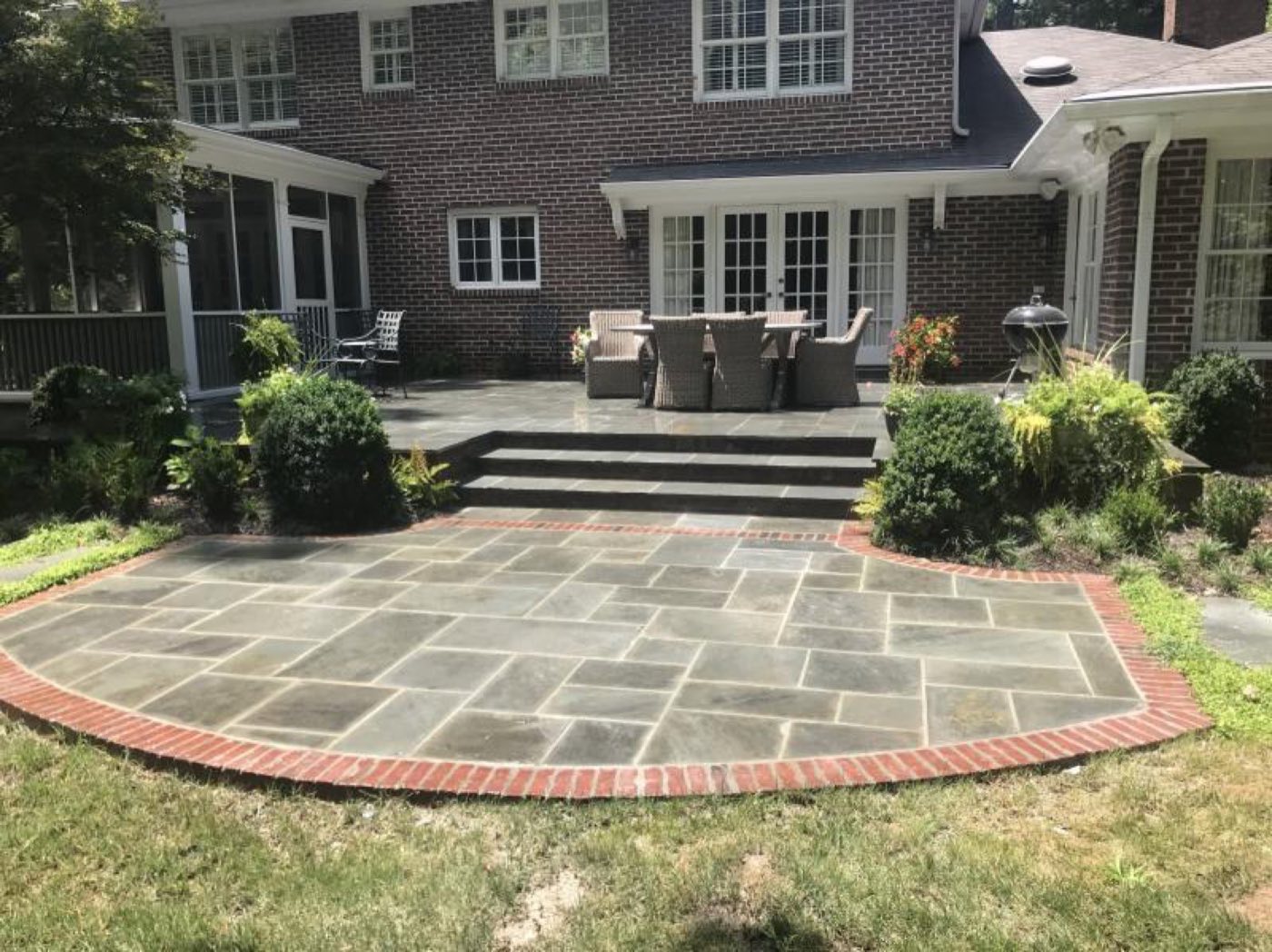 Bluestone patio bordered with a brick soldier course, with steps up to an upper terrace