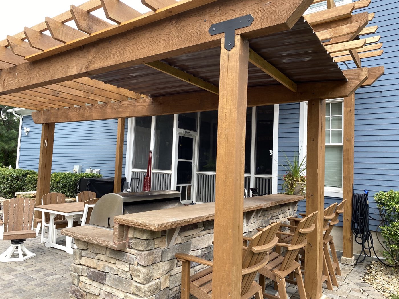 Timber pergola over a stone bar with a thick timber top and Adirondack bar stools