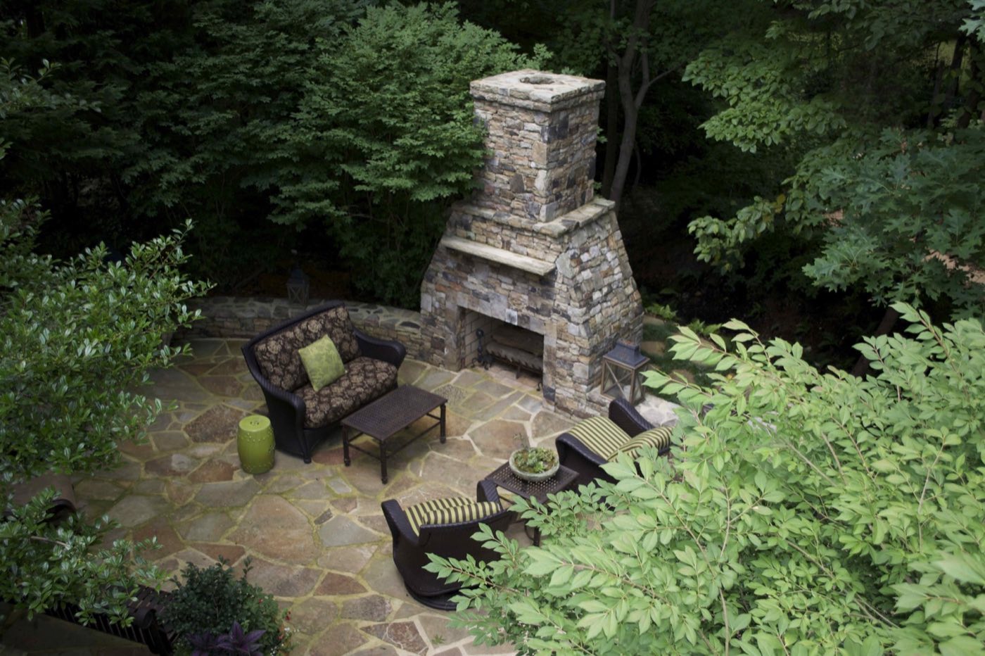 Stacked stone outdoor fireplace on a flagstone patio tucked into mature woods