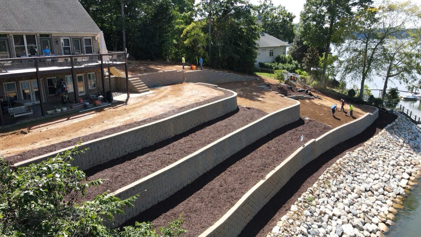 Crew installing tiers of a block retaining wall on a lakefront bank