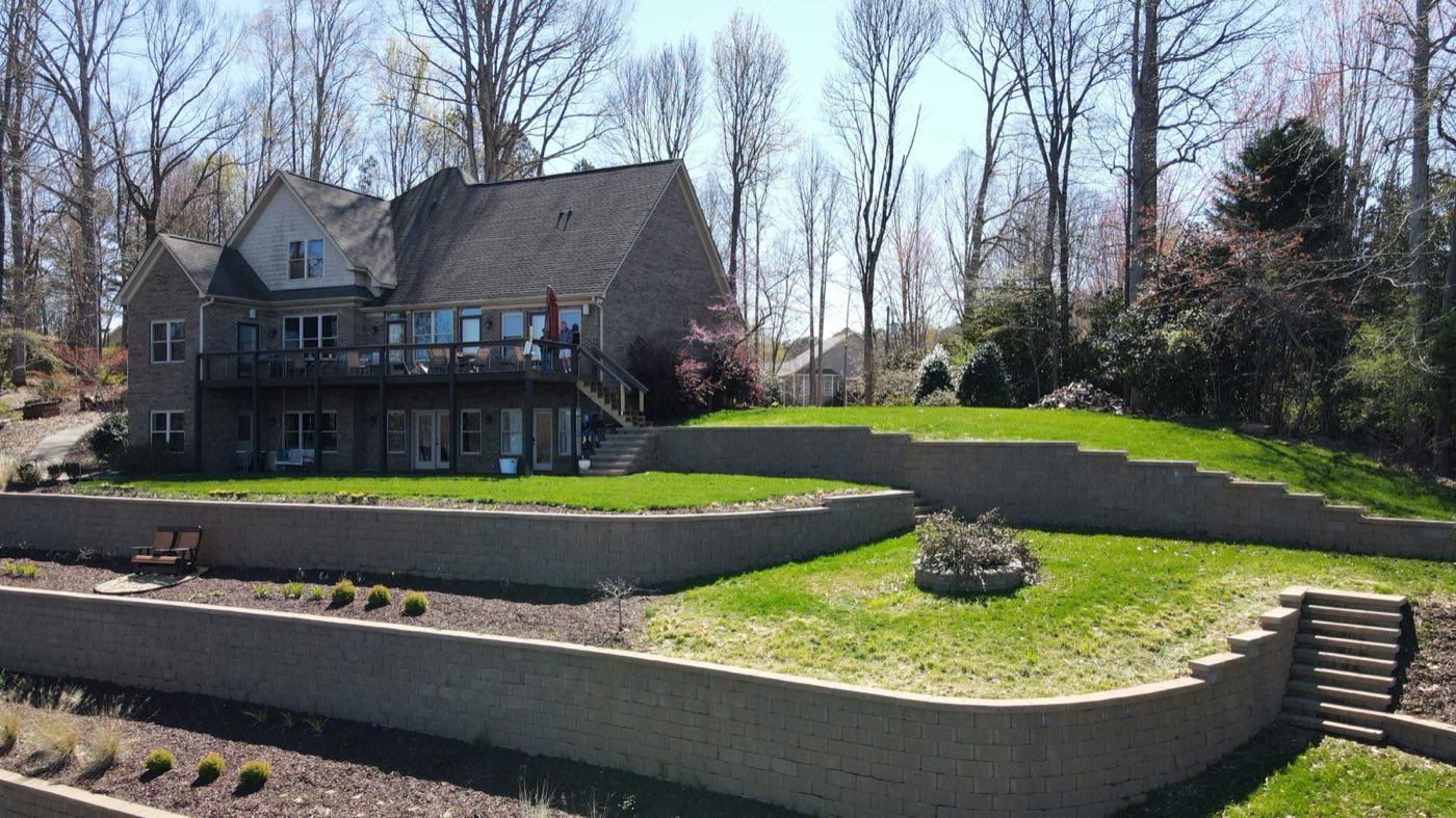 Curved block retaining walls stepping a Mooresville backyard down into level lawn
