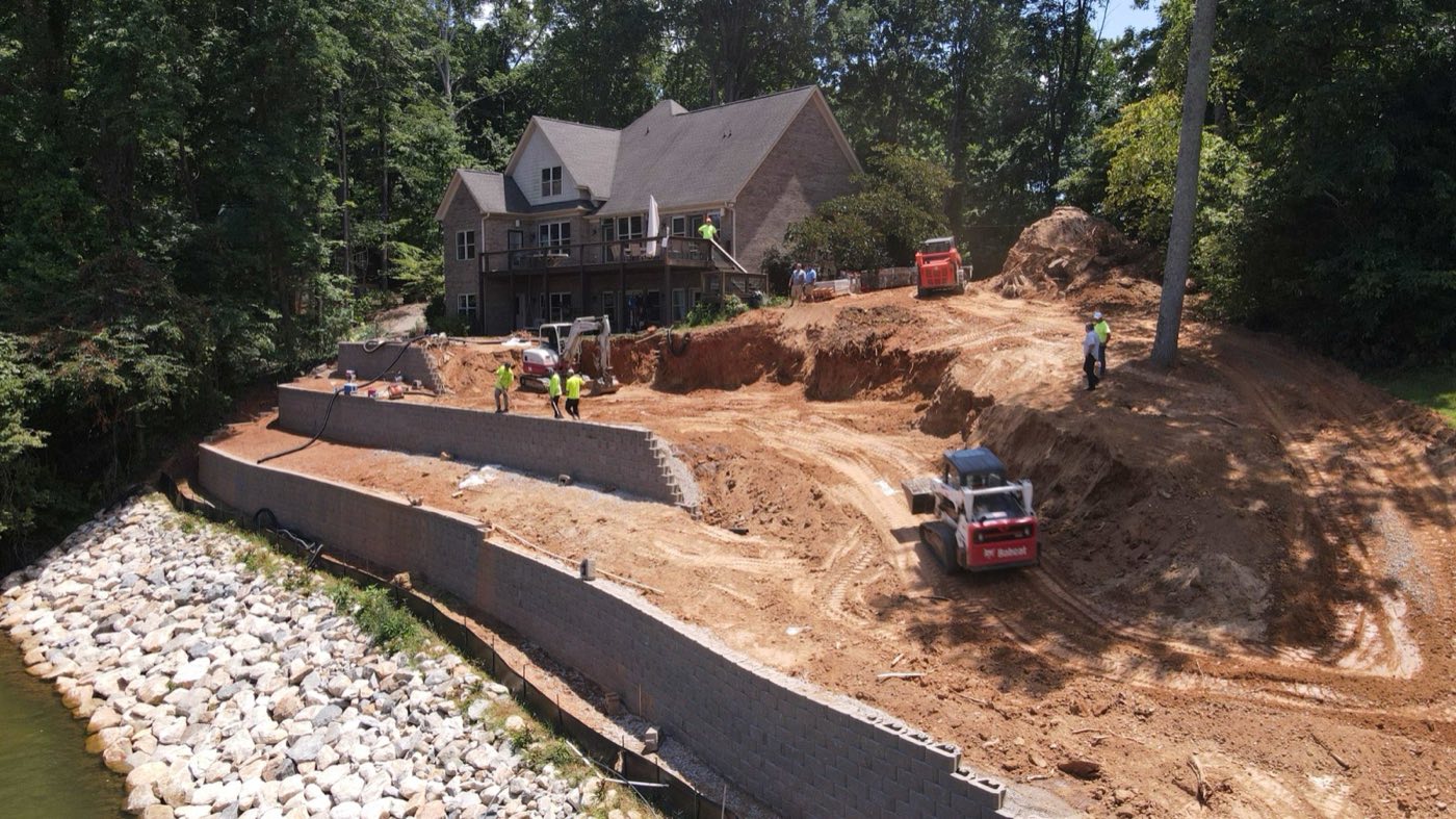 Crew building the tiered retaining wall on a Mooresville lakefront lot, excavation in progress