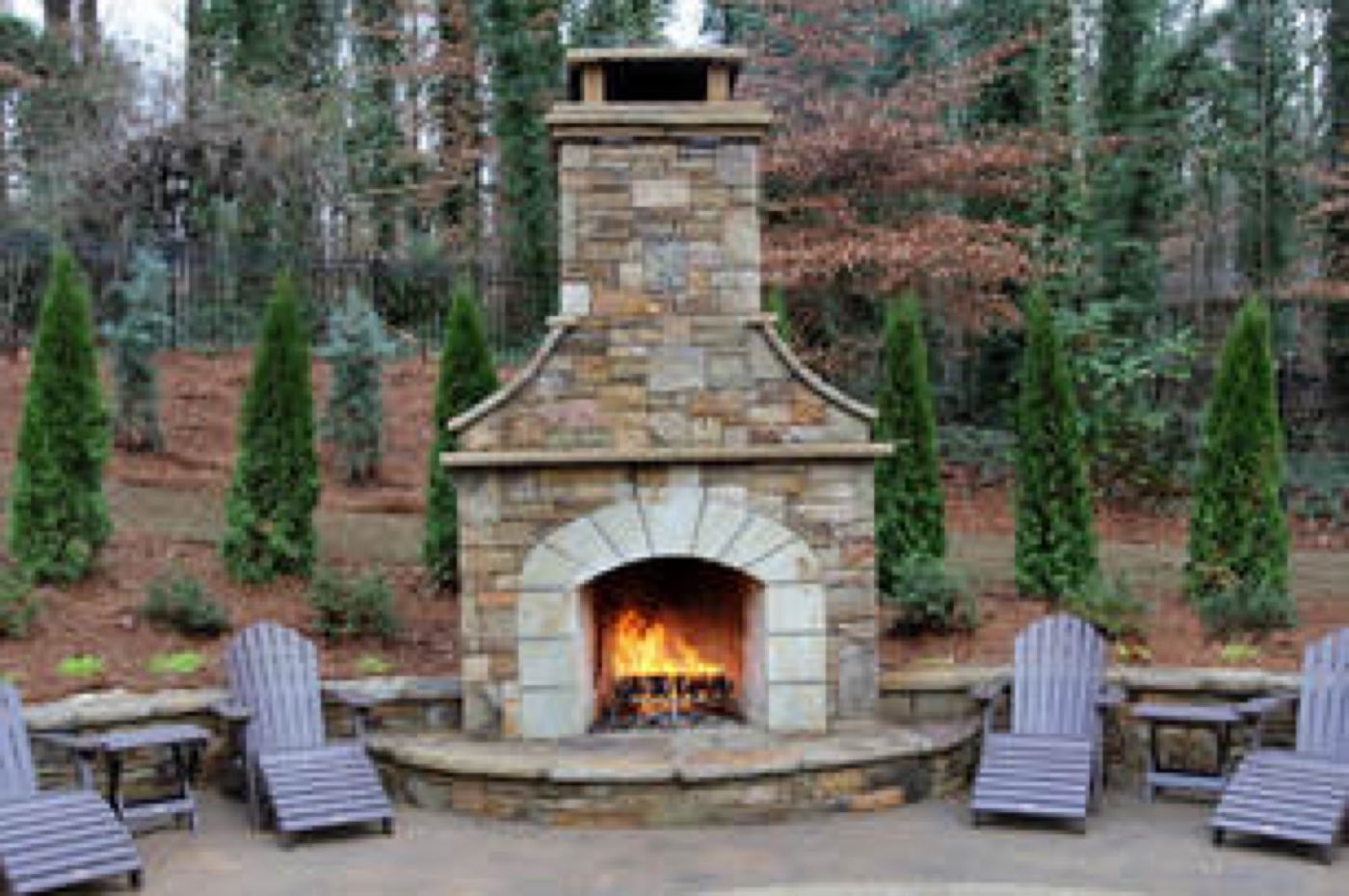 Stacked stone outdoor fireplace with an arched firebox and curved hearth seating