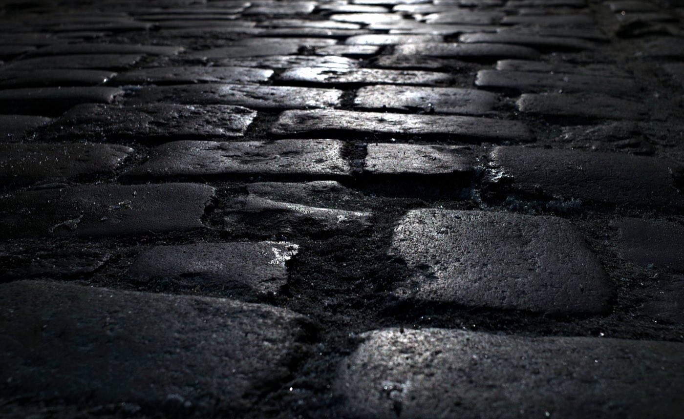 Wet cobblestone paving catching the light at night